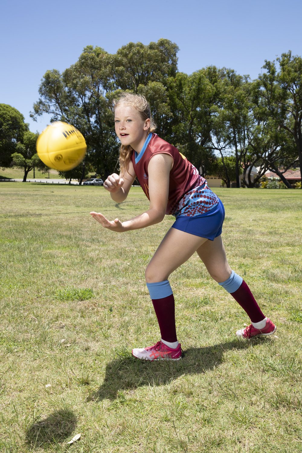 A junior player in club colours handballing a football