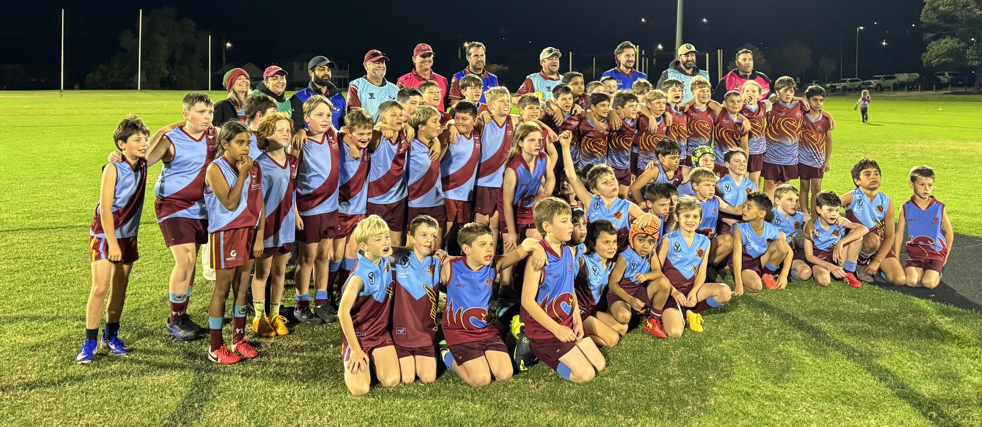 Junior players gathered on the oval at night under the lights
