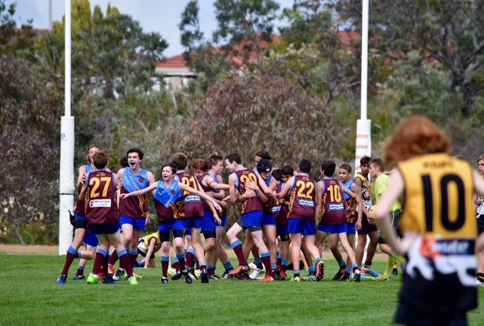 Junior players celebrating together in front of the goalposts